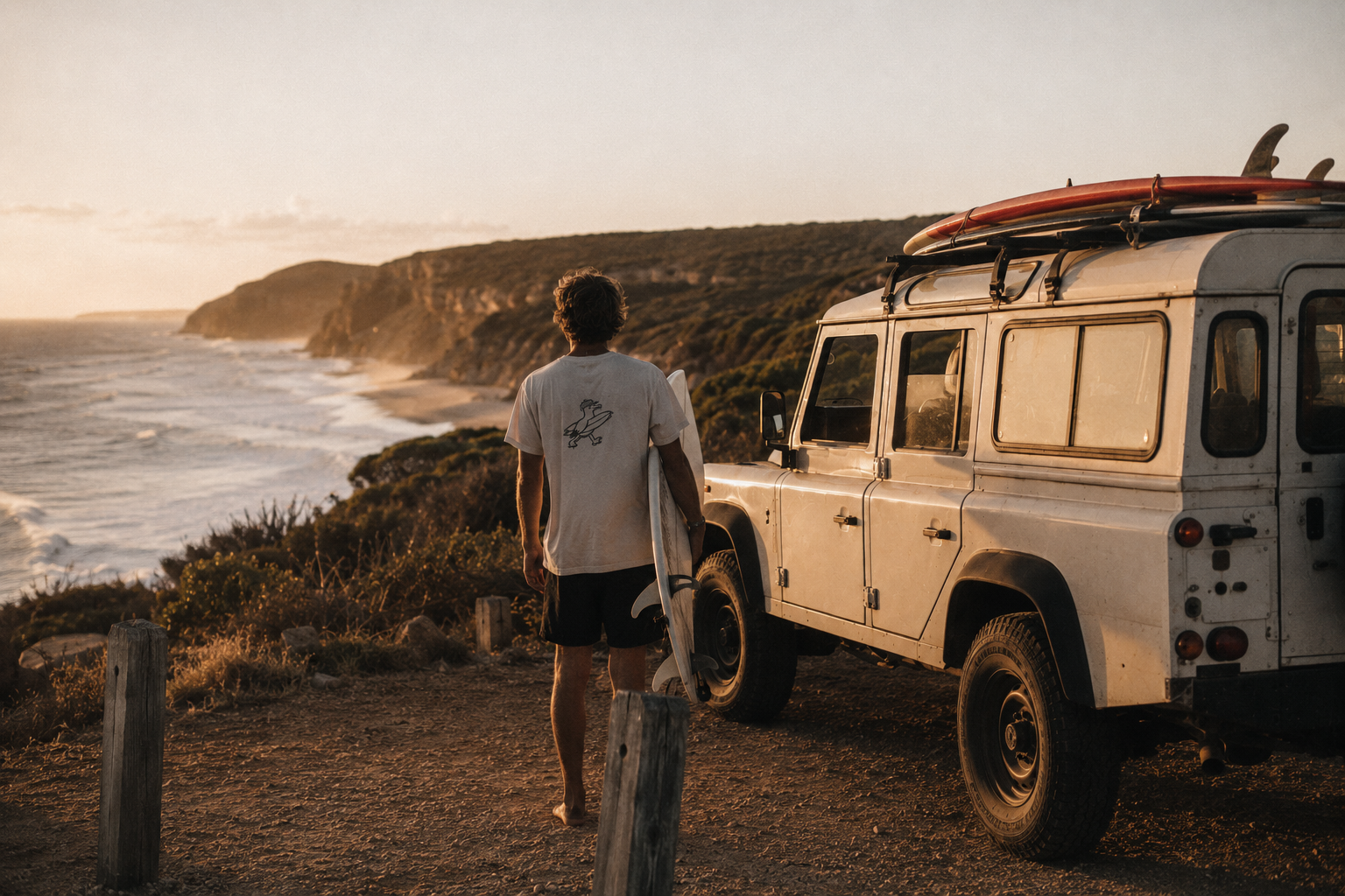 Surfer beside an old 4WD on the coast